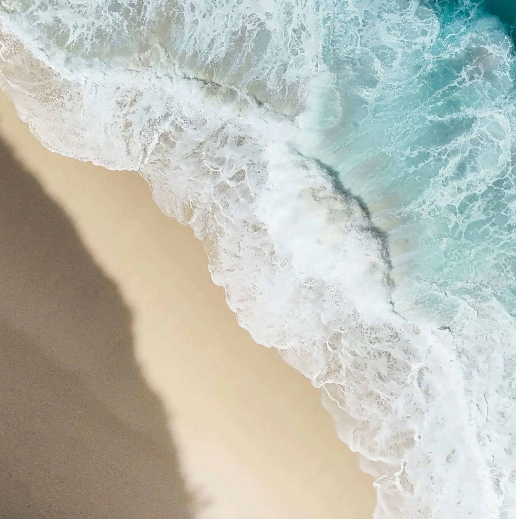 Aerial view of ocean waves crashing on a sandy beach