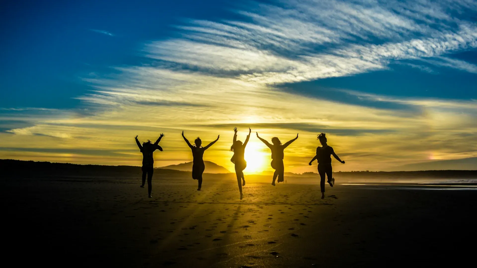 people jumping on shore front of golden hour